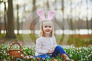 Girl wearing bunny ears playing egg hunt on Easter