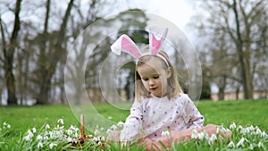 Girl wearing bunny ears playing egg hunt on Easter