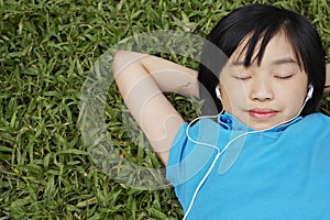 Girl Wearing Earphones While Lying On Grass