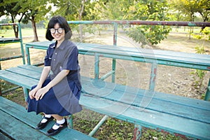 Girl wearing glasses sitting on the bench.