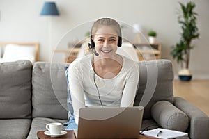 Girl wearing headset using laptop working or studying at home