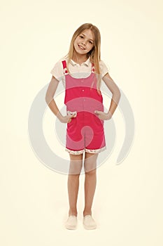 Girl wearing hot pink jumpsuit, white blouse and shoes. Cheerful kid in summer outfit, vacation concept. Child holding