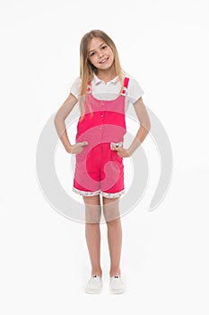 Girl wearing hot pink jumpsuit, white blouse and shoes. Cheerful kid in summer outfit, vacation concept. Child holding