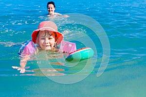 Girl is wearing inflatable armbands, learning to swim in the sea