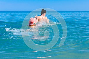 Girl is wearing inflatable armbands, learning to swim in the sea