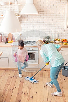 Girl wearing jeans and pink shirt helping mom with cleaning