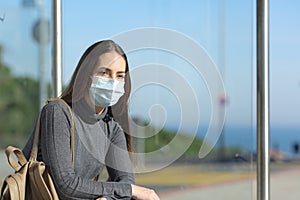 Girl wearing a mask preventing contagion in a bus stop photo