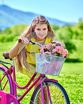 Girl wearing red polka dots dress rides bicycle into park.