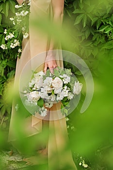 A girl wearing a romantic pink dress holding a bouquet of white roses, standing outdoors, green background Gentle pastel colors Cu