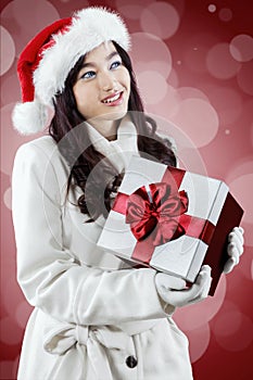 Girl wearing santa hat holding gift box