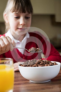 Girl Wearing School Uniform Eating Bowl Of Sugary Breakfast Cereal In Kitchen photo