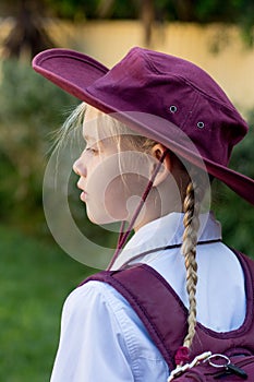 A girl wearing school uniform, white shirt, maroon backpack and a hat Back to school. Return to classrooms after COVID-19 outbreak