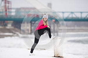 Girl wearing sportswear and doing stretching exercises on snow