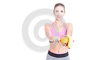 Girl wearing sportswear showing fruits and pills