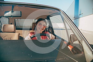 Girl wearing sunglasses sitting behind the wheel in the driver& x27;s seat