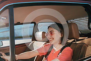 Girl wearing sunglasses sitting behind the wheel in the driver& x27;s seat