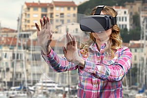Girl wearing VR glasses on city buildings background.