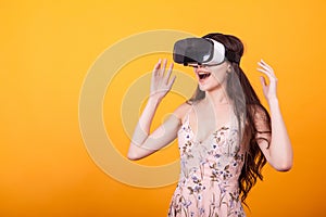 Girl wearing a VR headset and experiencing virtual reality, technology and innovation concept in studio over yellow