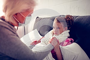 Girl wearing warm beige scarf having flue looking at granny