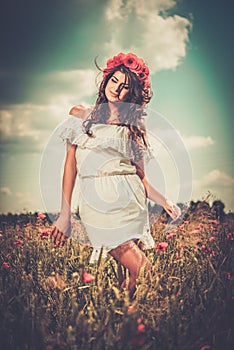 Girl wearing white summer dress in poppy filed photo
