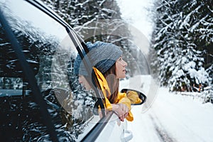 Girl wearing yellow jacket looking out of car among snowy road