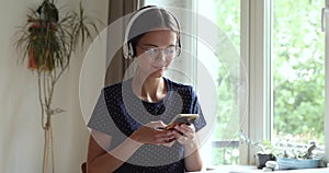 Girl wears headphones eyeglasses using cellphone texting message to friend