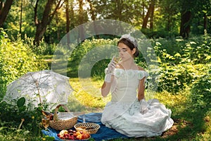 Girl in a wedding dress in the park on a sunny day on a picnic with