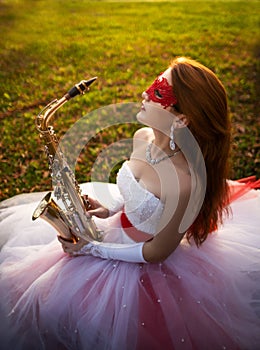 Girl in a wedding dress with a saxophone in an autumn park