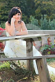 Girl in the wedding dress sitting on the bench