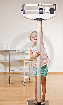 Girl weighing herself in doctor office photo