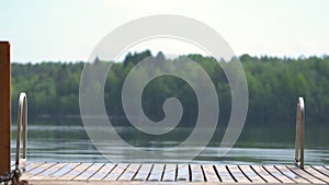 Girl in wetsuit jumping into the lake from wooden pier. Having fun on summer day