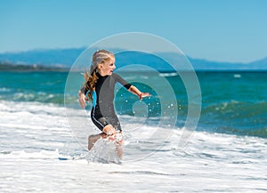 Girl in a wetsuit running along the beach