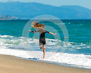 Girl in a wetsuit running along the beach