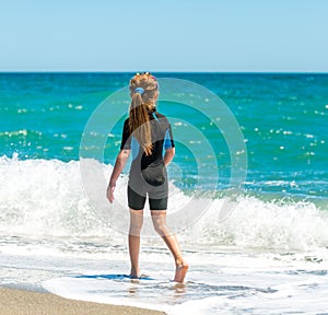 Girl in a wetsuit running along the beach