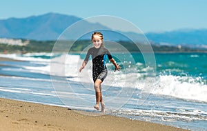 Girl in a wetsuit running along the beach