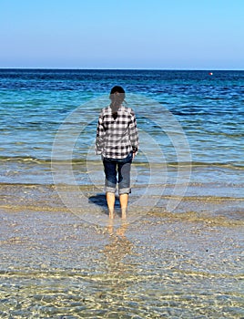 Girl wetting her feet by the sea in Mondello