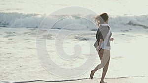 Girl wetting her hands in the water and running on the coast of the sea