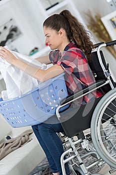 Girl on wheelchair folding clothes