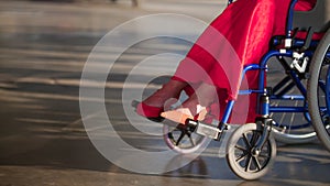 Girl in a wheelchair, in the frame of female legs in red shoes