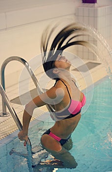 Girl whipping her hair back in the pool and spraying water everywhere splash