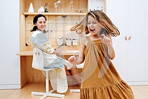 Girl whirls in the childrens room against the background of her mother