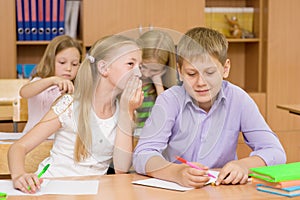 Girl whispering secrets of the boy in the classroom