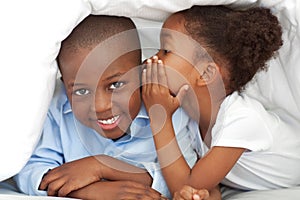 A girl whispering something to her brother