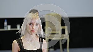 Girl with white albino hair moving on runway catwalk podium. Female model defile