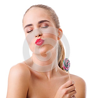 A girl on a white background with closed eyes sends an air kiss with a lollipop in her hands.