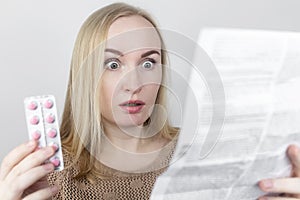 The girl on a white background reads the instructions for medicines. The woman looks at the list and composition of the drug. The