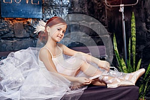 Girl in a white ball gown and shoes, beautiful red hair. Young theater actress. Little prima ballet. Young ballerina girl