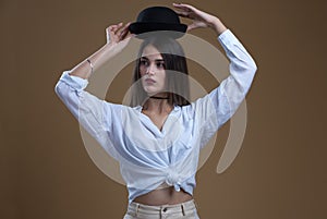 A girl in a white blouse with a black hat on a beige background