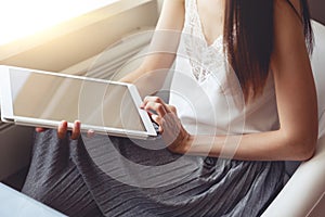 Girl in white blouse and grey skirt using tablet idoors