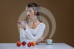 A girl in a white blouse with peaches on a beige background